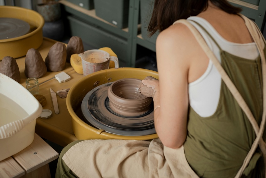 Hands shaping clay on a pottery wheel